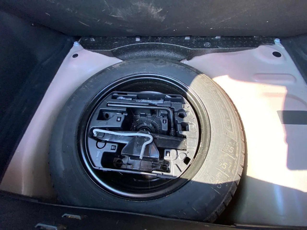 Gros plan sur la roue de secours acier 15 pouces dans le coffre d'une Citroën C3 orange 2018.