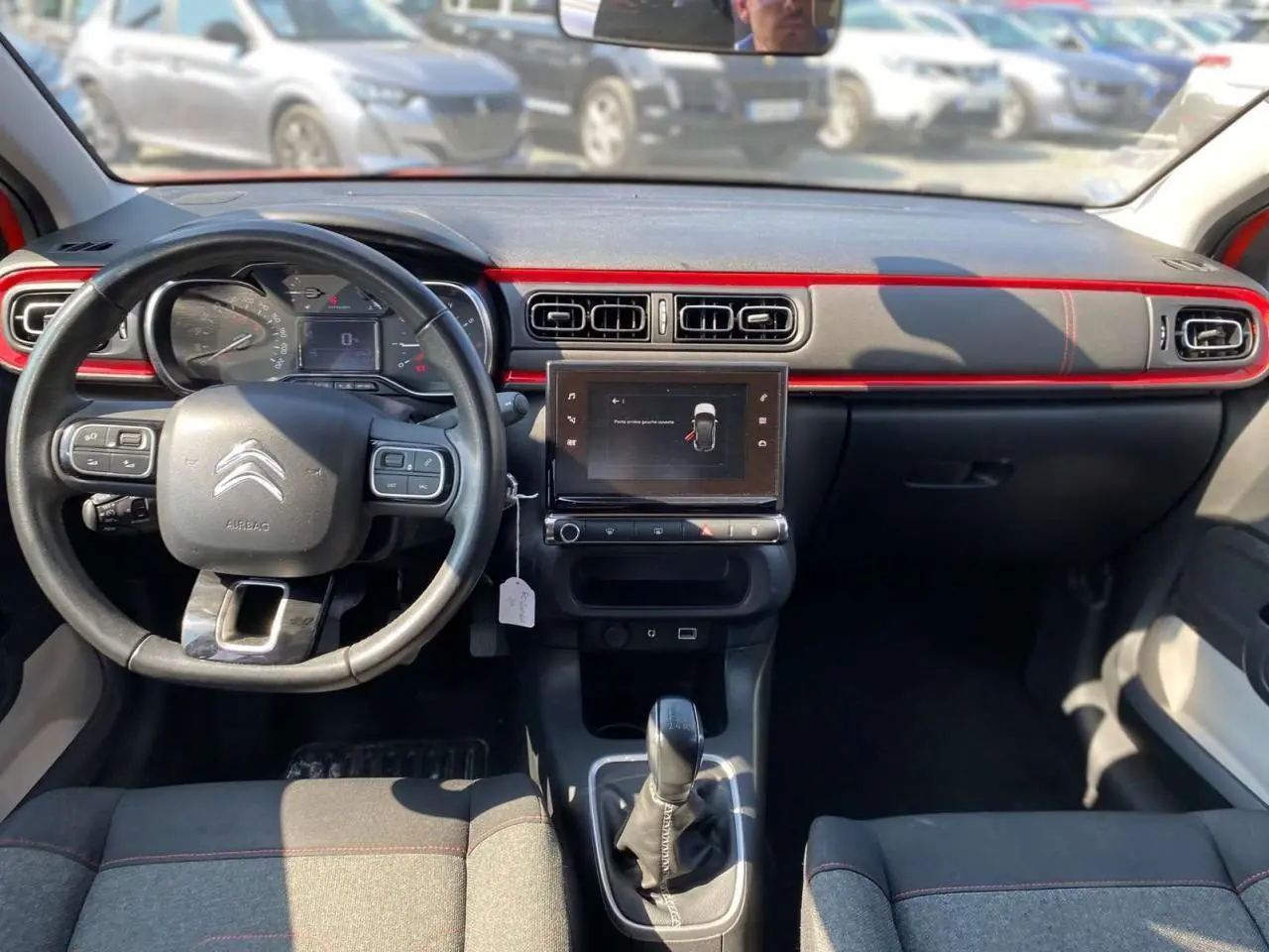 Vue intérieure avant de la Citroën C3 orange 2018, tableau de bord noir avec bande rouge et écran tactile central.