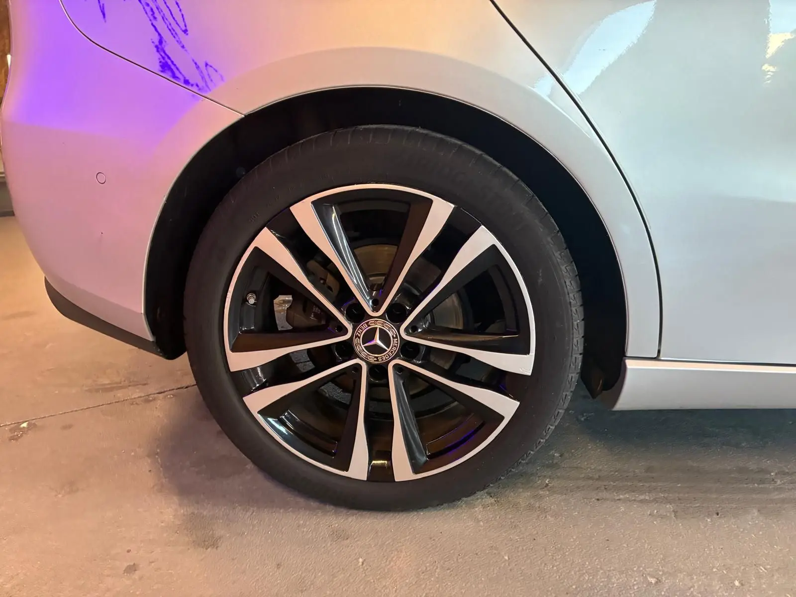 Gros plan sur la roue arrière droite d’une Mercedes Classe B 200D gris métallisé avec jante alliage noire et argent.