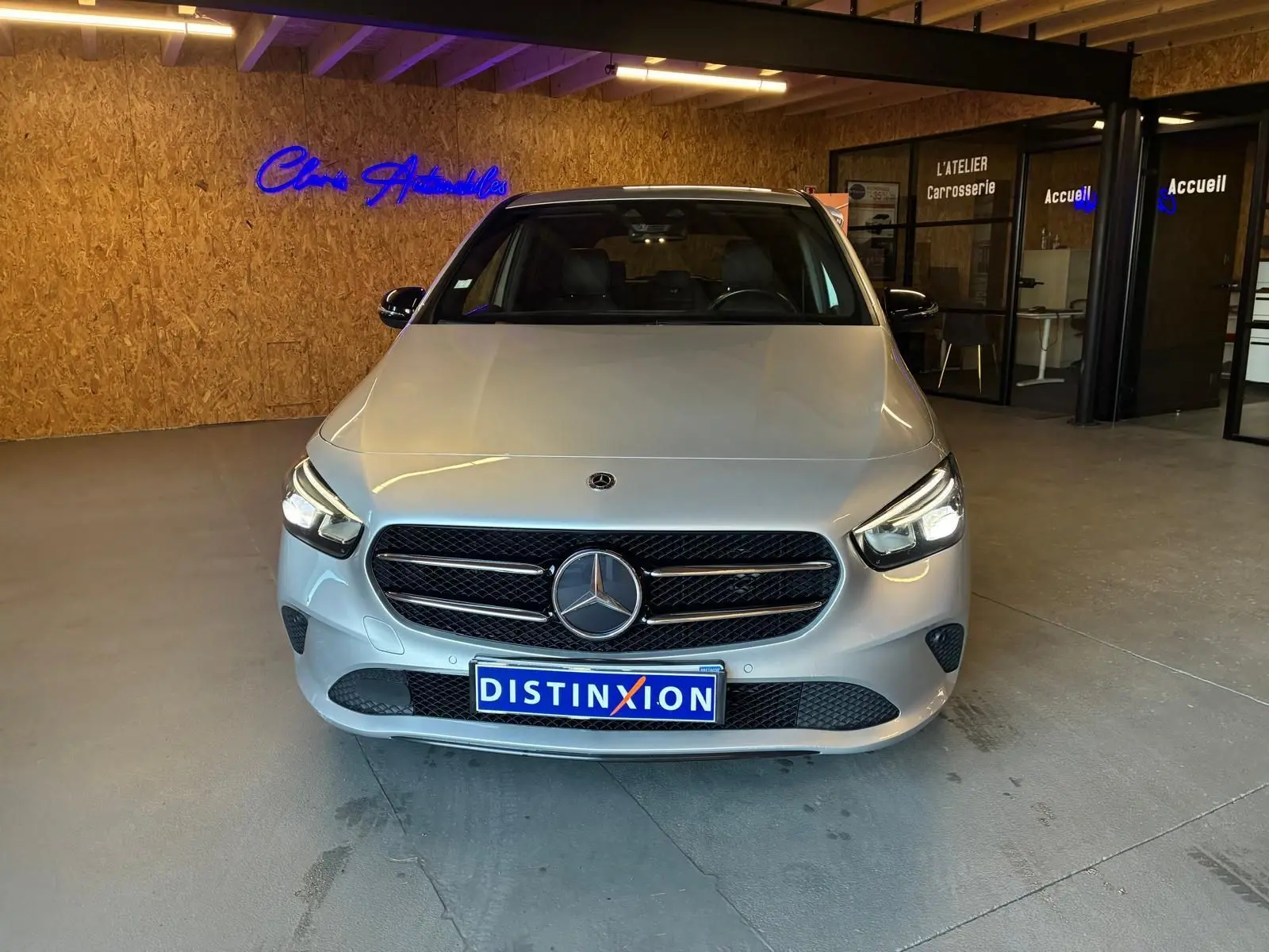 Vue avant d'une Mercedes Classe B 200D Progressive Line gris métallisé, avec calandre noire et logo central lumineux.