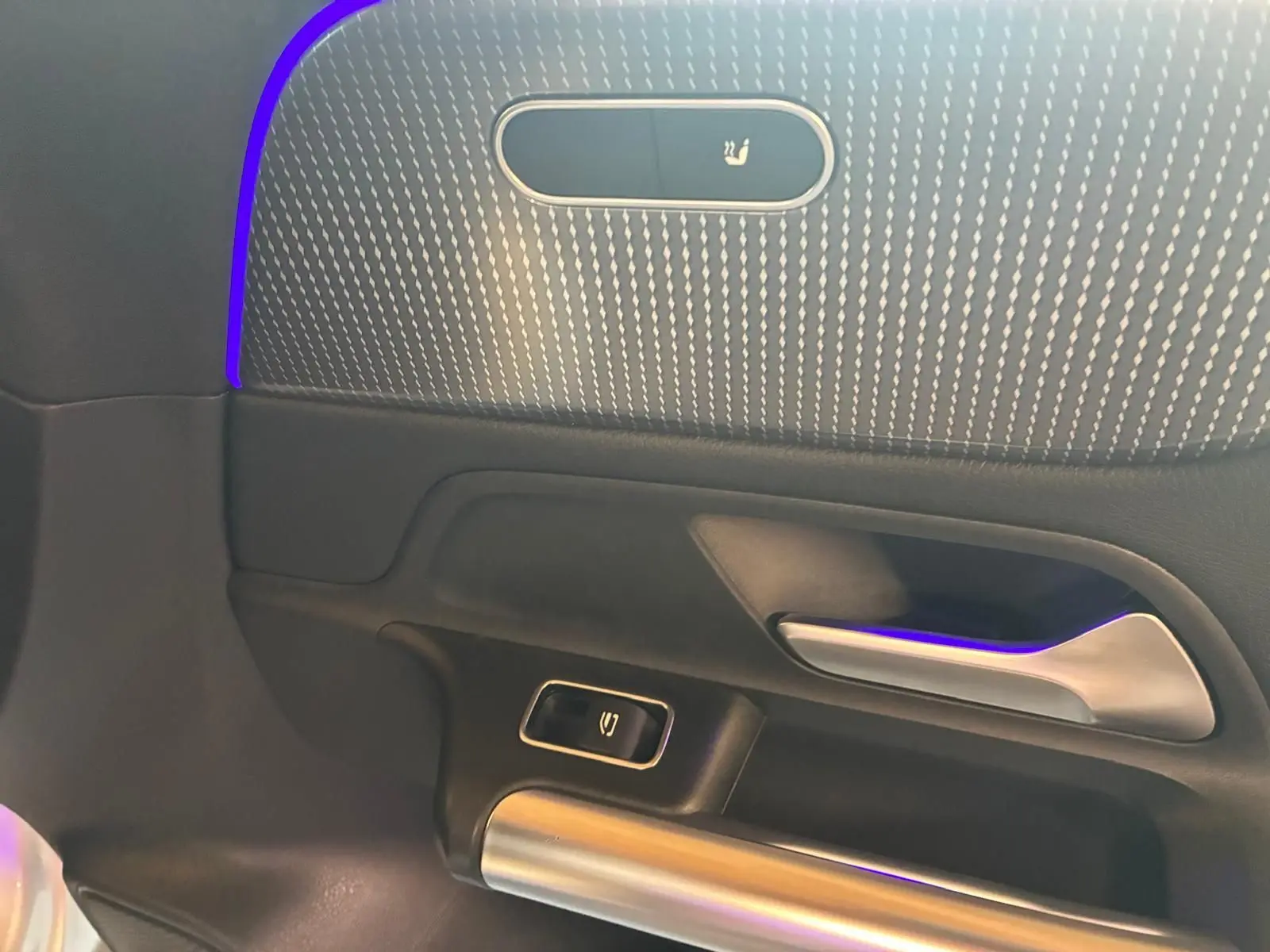 Détail de la porte côté gauche de la Mercedes Classe B 200D gris, avec éclairage d'ambiance violet et bouton de verrouillage.