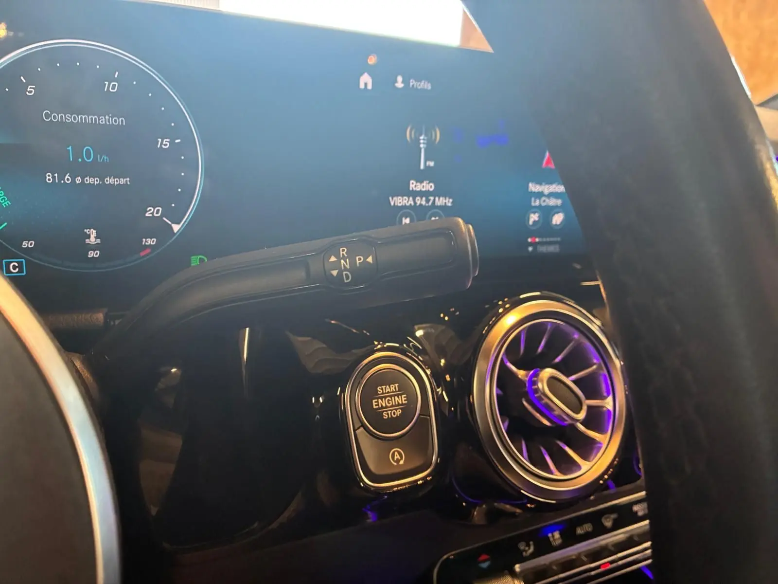 Gros plan intérieur sur la console centrale d'une Mercedes Classe B 200D grise, avec bouton start/stop et commandes de boîte auto.