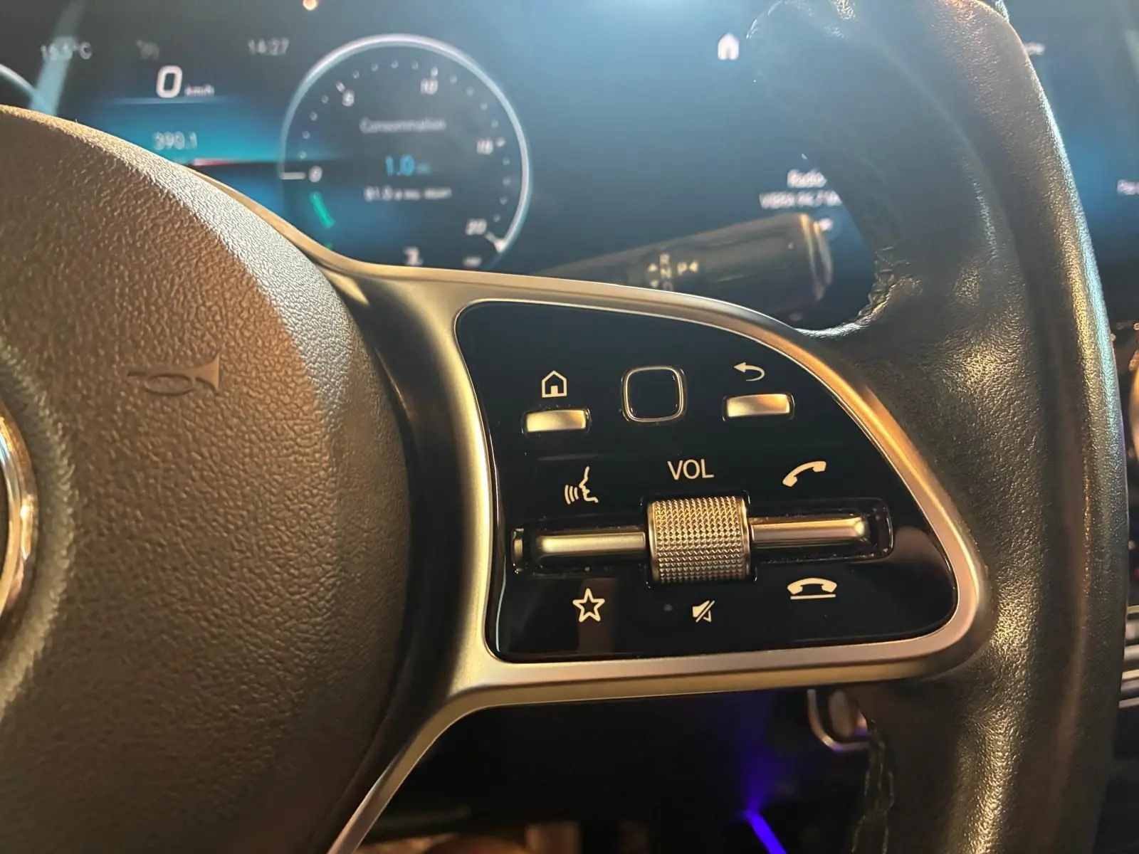 Gros plan sur la commande de volume au volant cuir noir d'une Mercedes Classe B 200D gris, avec tableau de bord numérique.