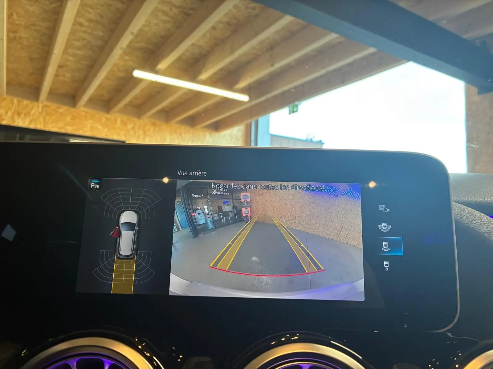 Écran intérieur de la Mercedes Classe B 200D montrant la caméra de recul avec guidage et capteurs de stationnement.