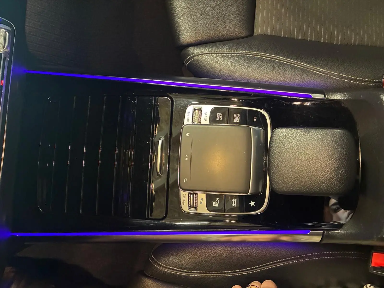 Vue rapprochée du pavé tactile central noir avec éclairage d'ambiance violet dans l'intérieur gris-noir d'une Mercedes Classe B 200D 2019.