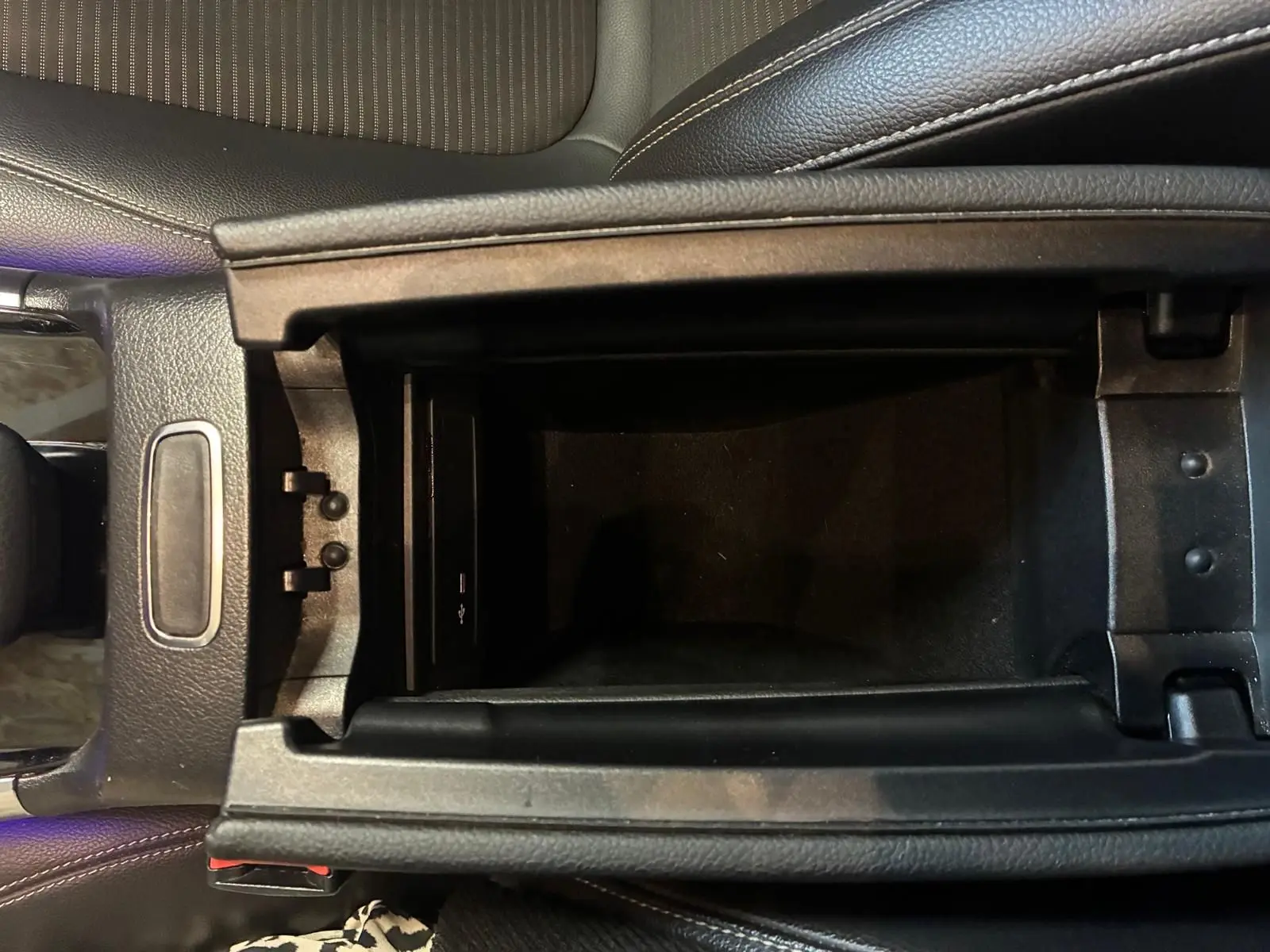 Vue rapprochée de la console centrale ouverte d'une Mercedes Classe B 200D gris, montrant le rangement intérieur et port USB.
