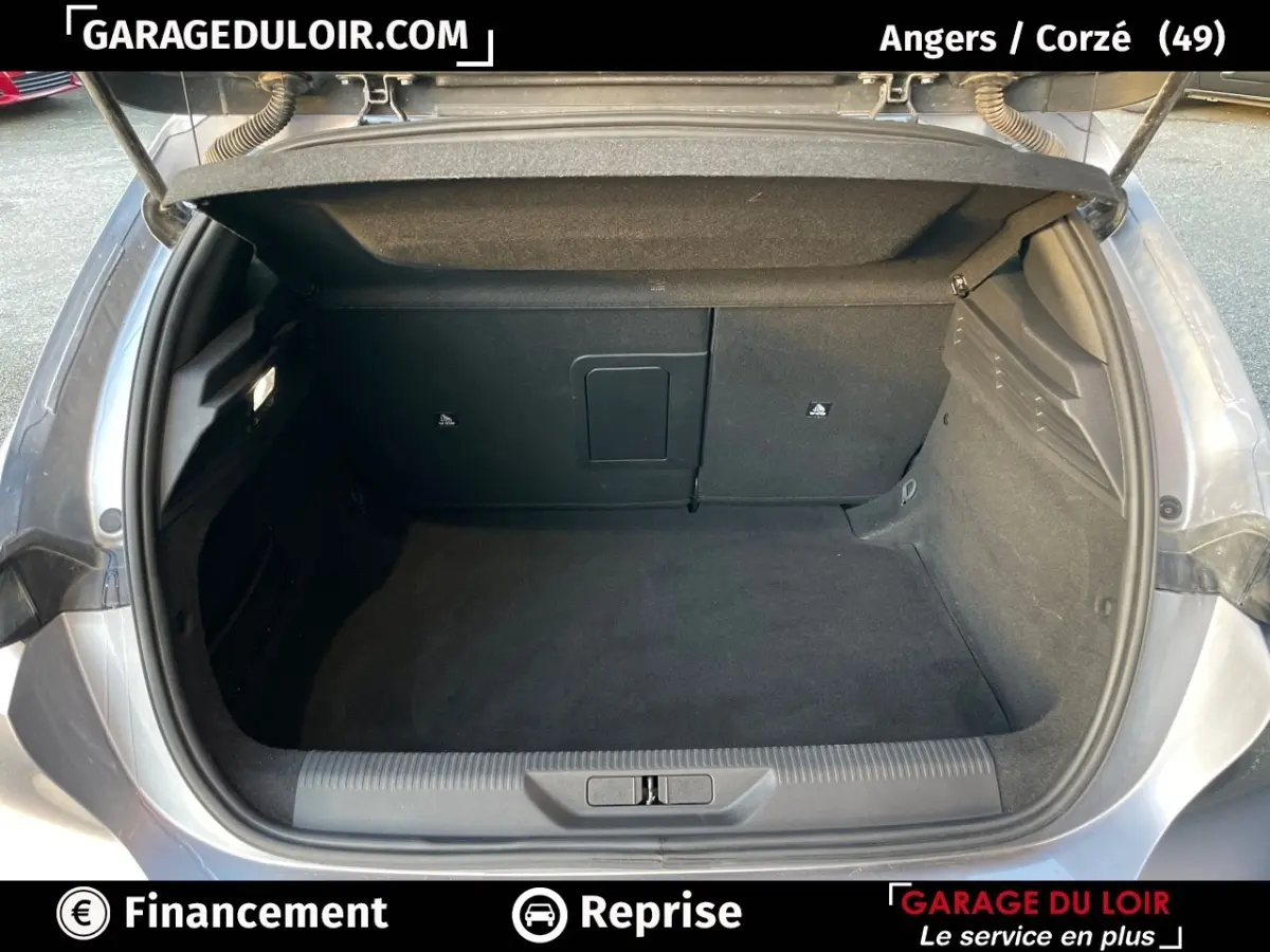 Coffre ouvert vu de l'arrière d'une Peugeot 308 gris foncé 2024, intérieur spacieux et propre sans chargement visible.