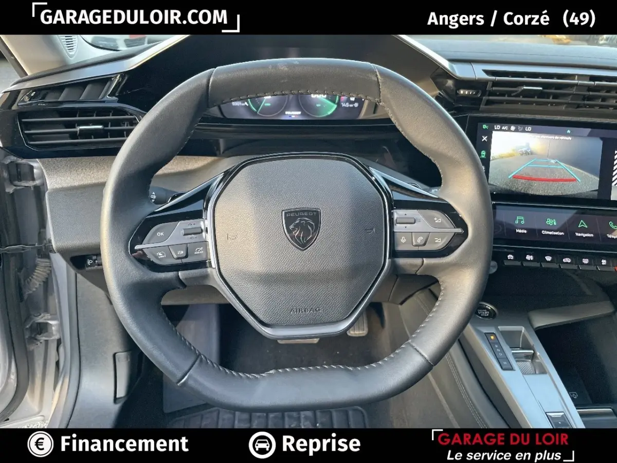 Vue intérieure centrée sur le volant noir de la Peugeot 308 2024, avec tableau de bord numérique et écran tactile visible.