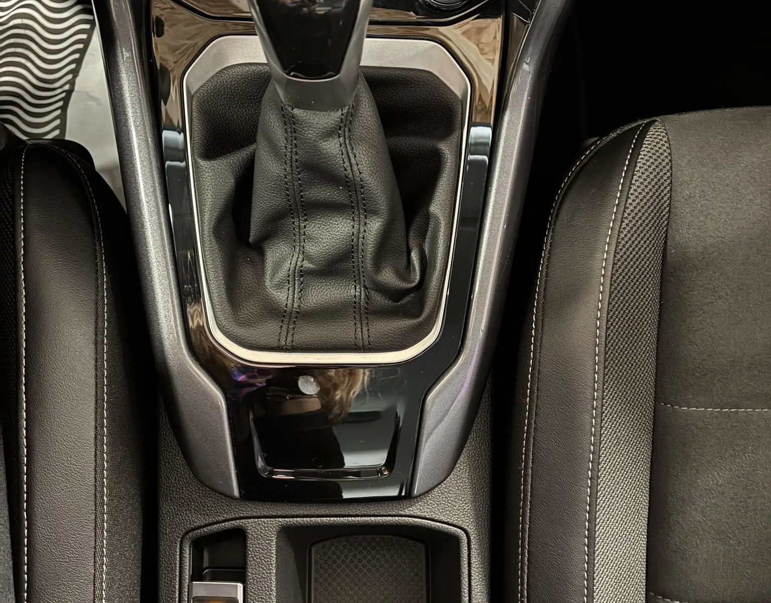 Vue plongeante sur la console centrale noire du Volkswagen T-Roc 2025, mettant en valeur le levier de vitesse automatique et les commandes adjacentes.