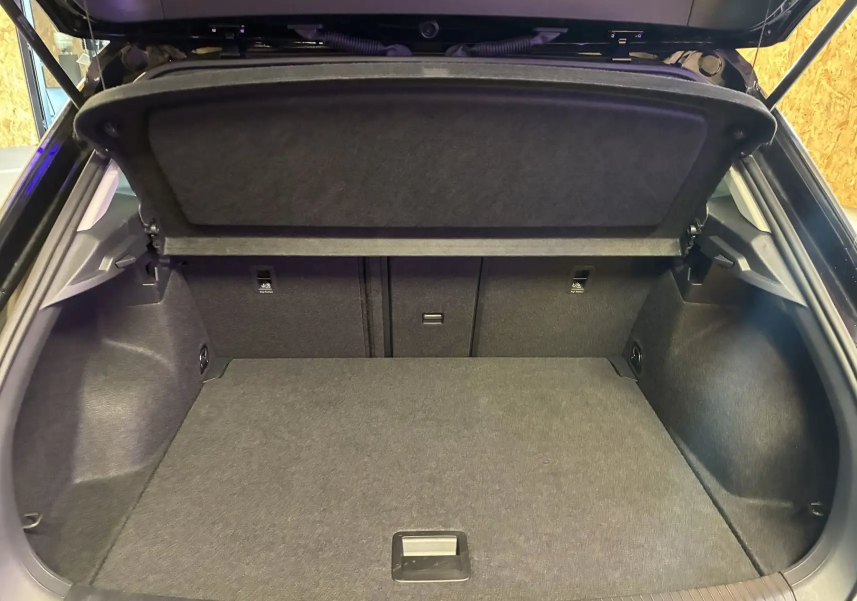 Vue intérieure du coffre ouvert du Volkswagen T-Roc noir 2025, montrant un espace de rangement propre et spacieux.