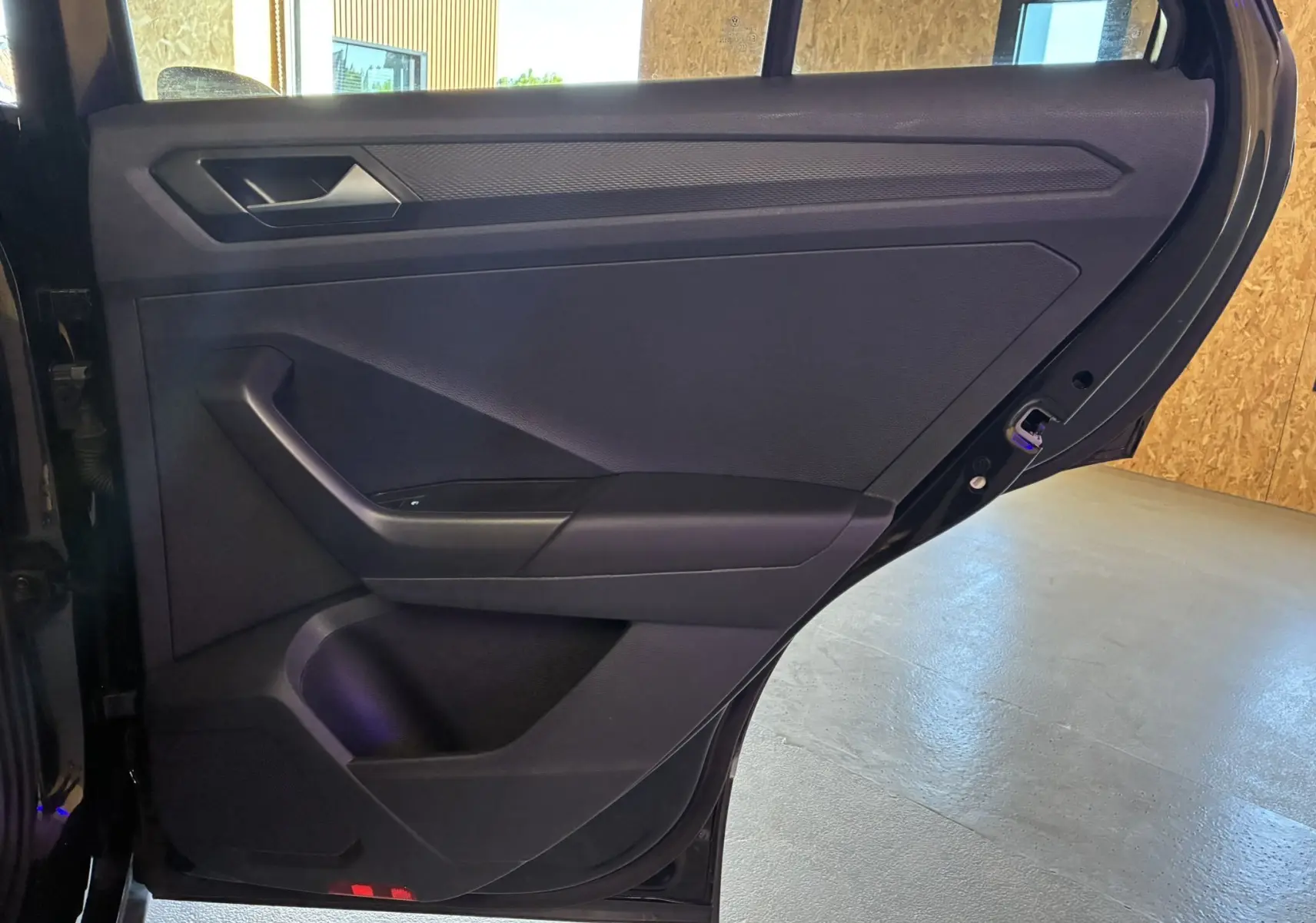 Vue rapprochée de la porte arrière gauche noire du Volkswagen T-Roc 2025, mettant en valeur son intérieur tissu noir.