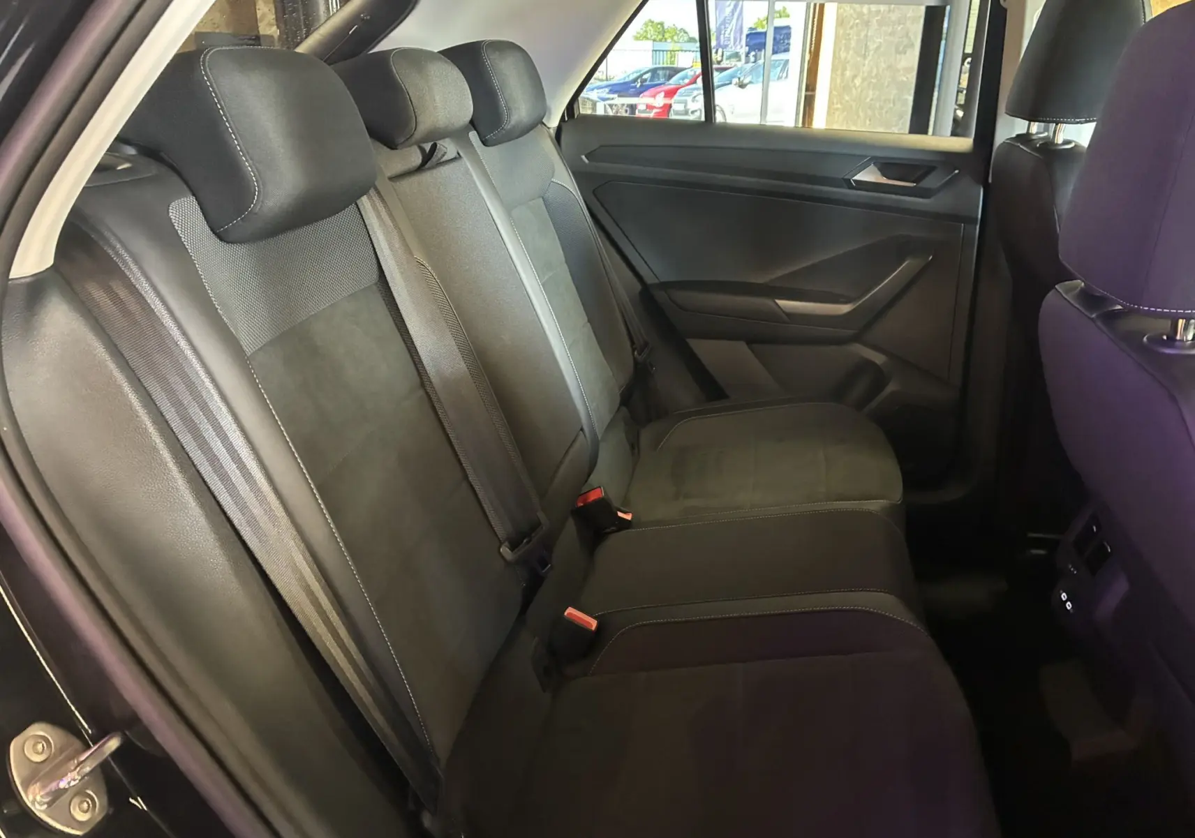 Vue intérieure côté gauche des sièges arrière noirs en tissu du Volkswagen T-Roc 2025, avec ceintures et appuie-têtes visibles.