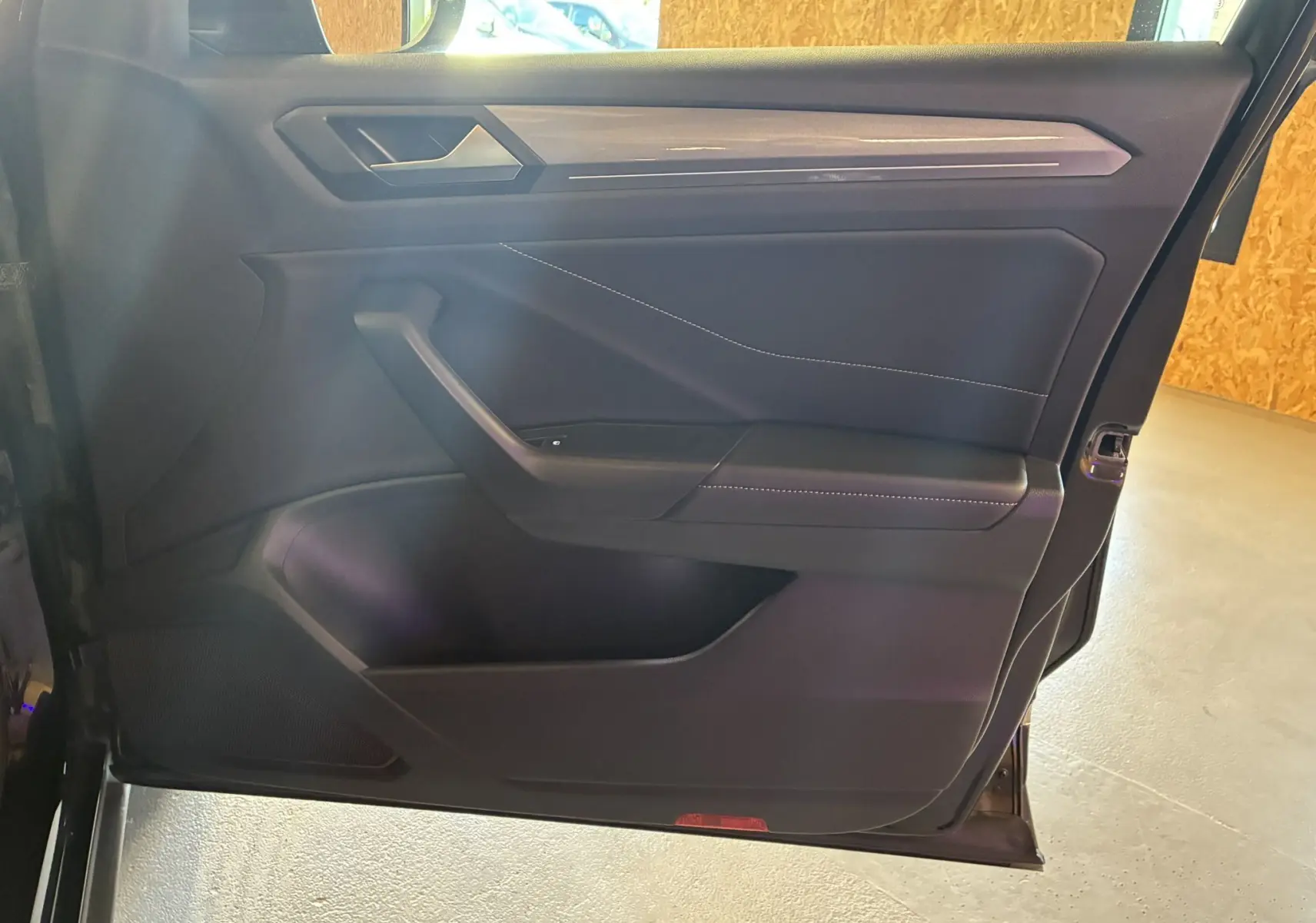 Vue intérieure de la porte avant droite noire du Volkswagen T-Roc 2025, avec garniture en tissu noir et surpiqûres contrastantes.