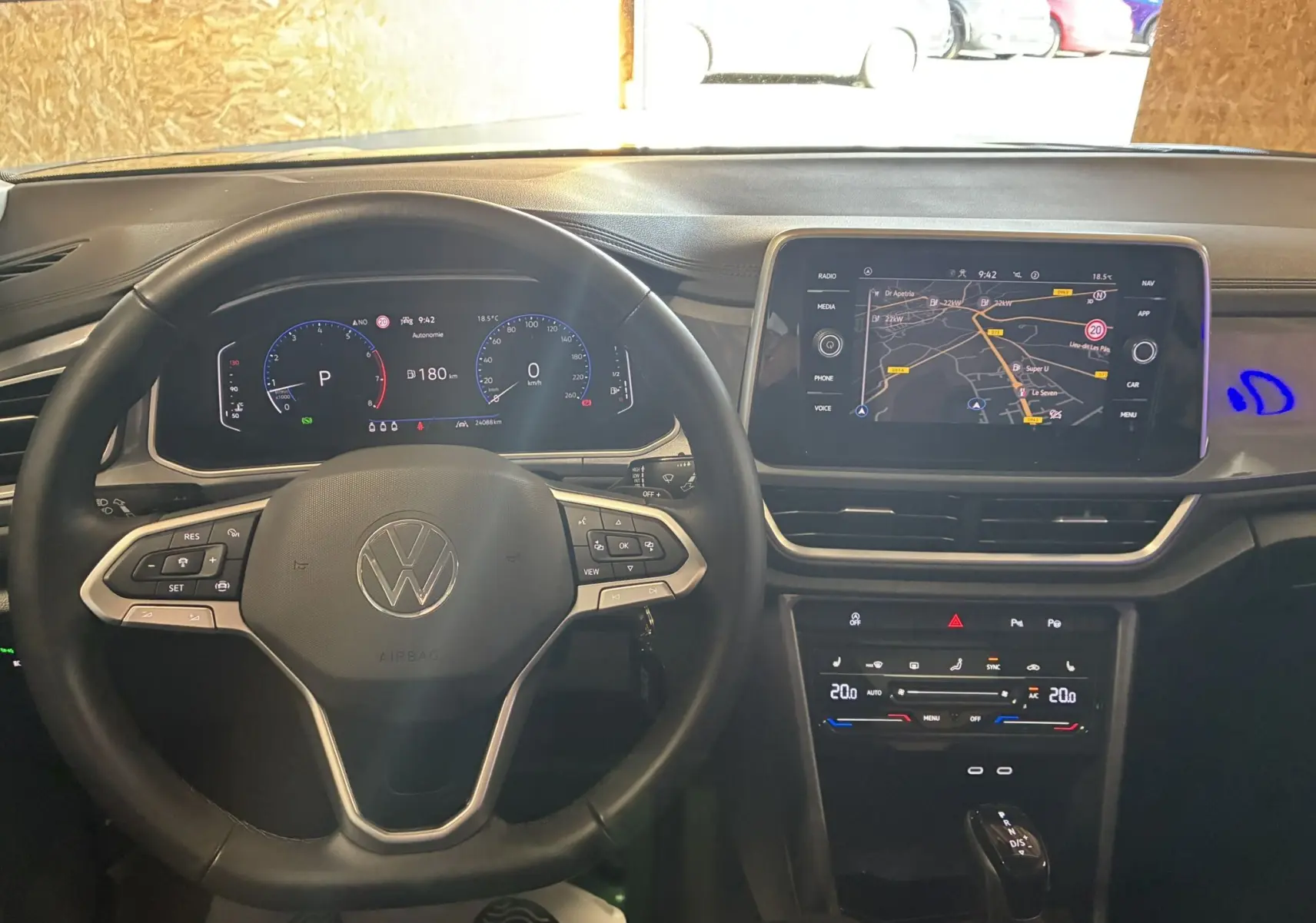 Vue intérieure du tableau de bord noir du Volkswagen T-Roc 2025, avec volant multifonction et écran tactile GPS allumé.