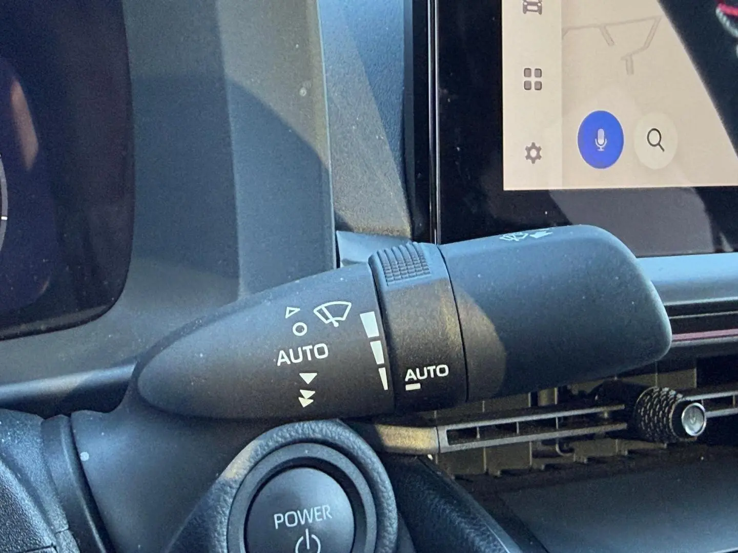 Gros plan sur la commande d'essuie-glace automatique à gauche du volant dans l'habitacle du Toyota C-HR gris Atlas.