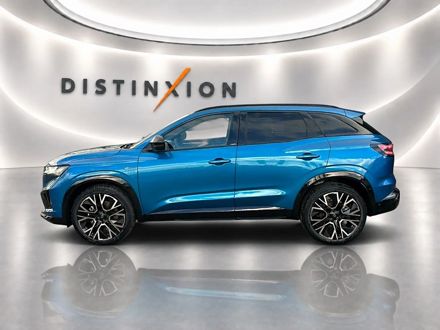 Profil droit du Renault Austral bleu outremer avec jantes alu noires et toit noir dans un showroom lumineux.