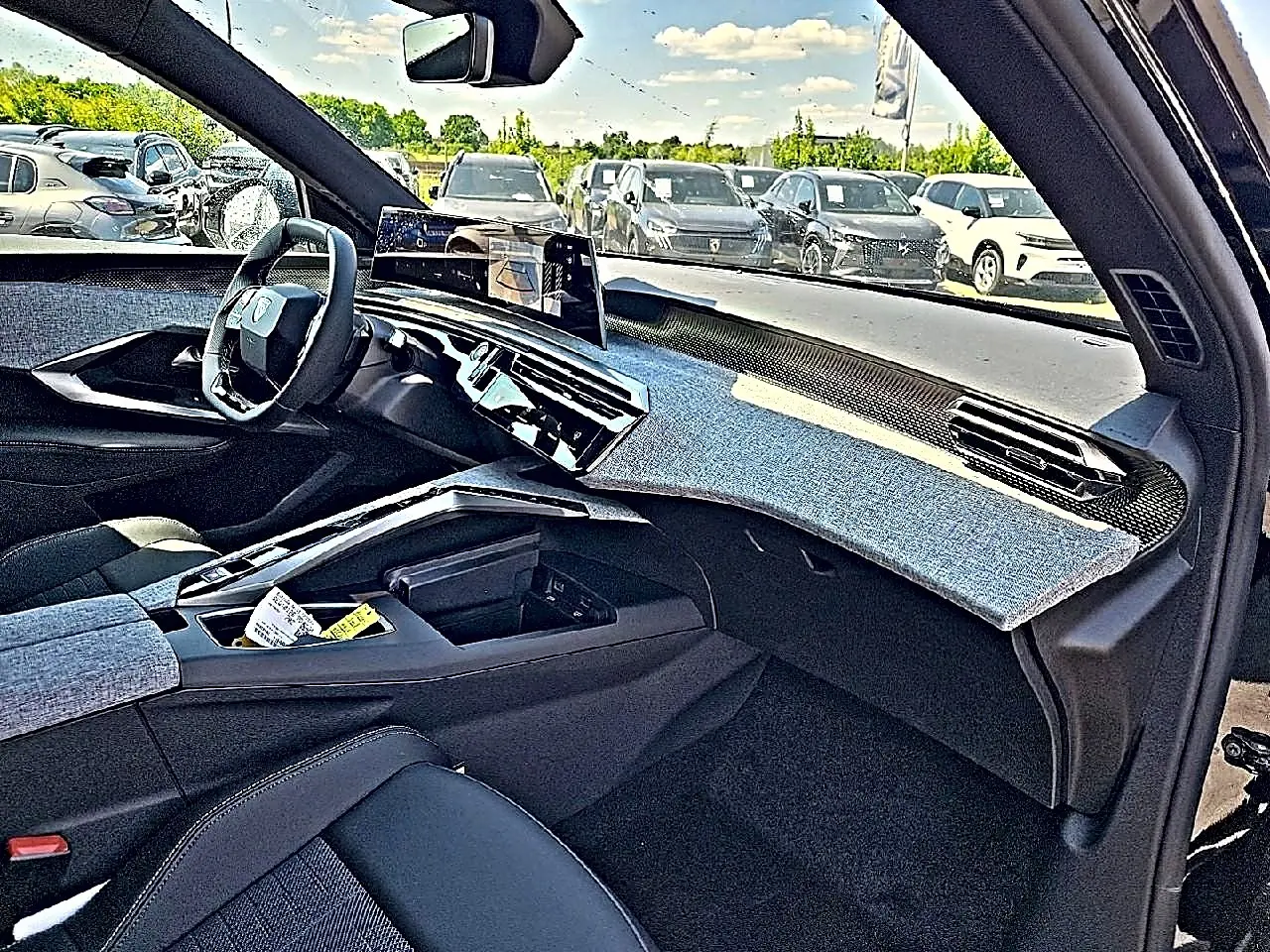 Vue intérieure côté passager du Peugeot 3008 noir 1.2 hybrid 2026, tableau de bord avec habillage tissu gris et écran tactile central.