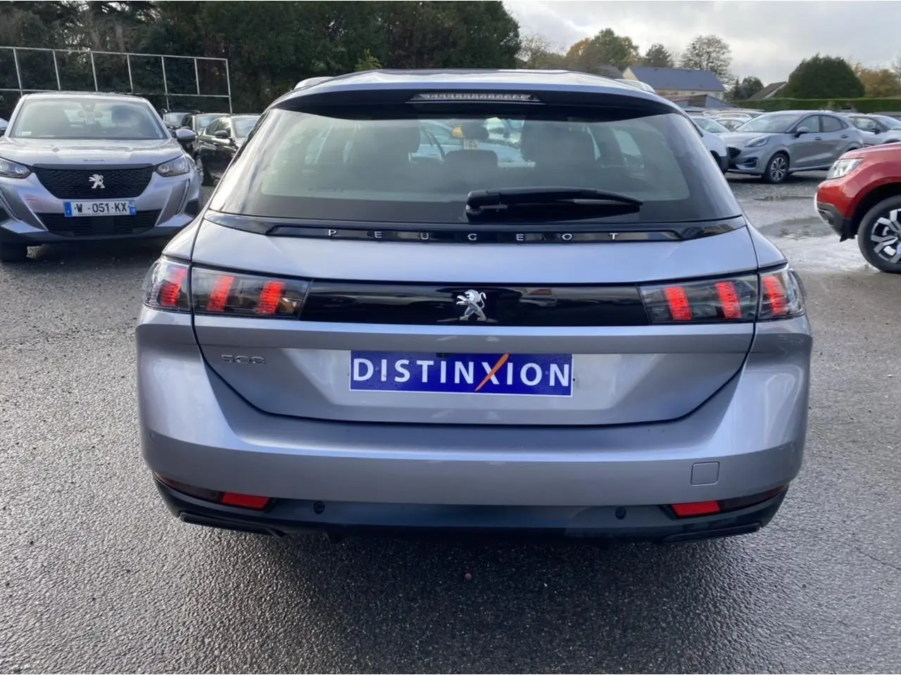 Vue arrière d'un Peugeot 508 SW gris Artense avec feux arrière à effet griffes et logo distinctif au centre.