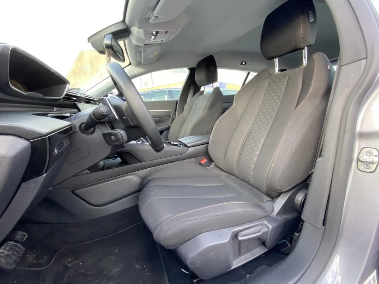 Vue intérieure côté conducteur de la Peugeot 508 SW gris Artense, sièges avant en tissu noir avec surpiqûres contrastées.