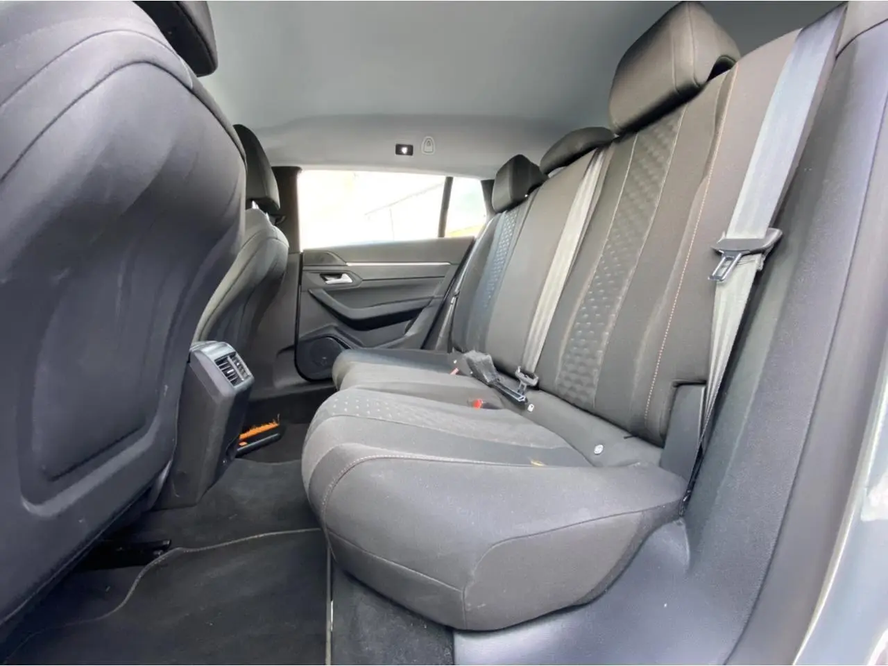 Vue latérale intérieure des sièges arrière noirs de la Peugeot 508 SW gris Artense, montrant l'espace et les ceintures de sécurité.