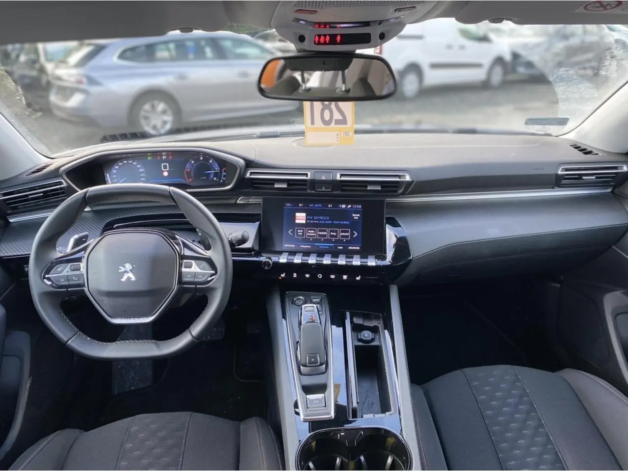 Intérieur de Peugeot 508 SW 2021 vu de face, tableau de bord moderne avec écran tactile et volant compact noir.