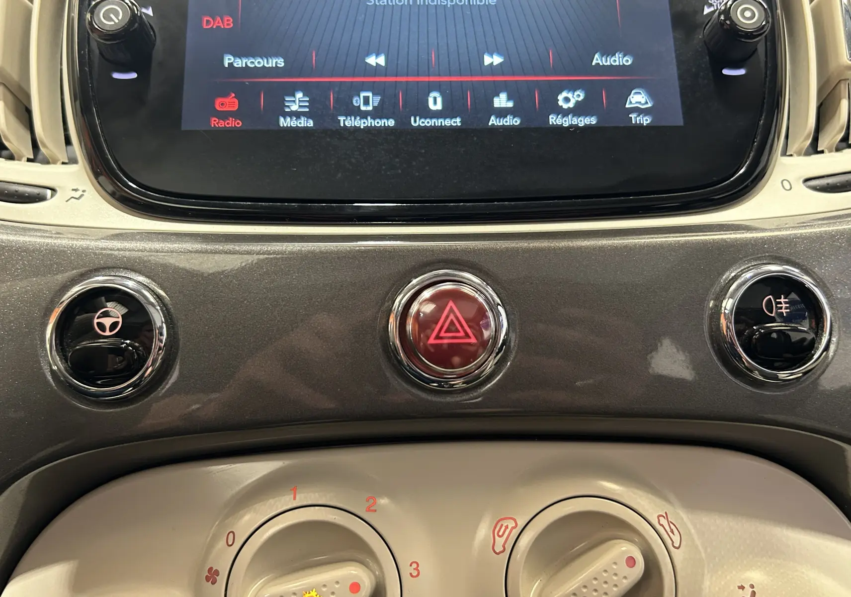 Gros plan sur la console centrale grise du tableau de bord du Fiat 500 70 Hybride BSG DolceVita avec écran tactile et commandes circulaires.