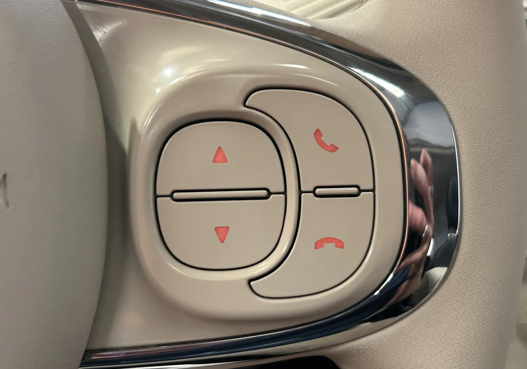 Gros plan sur les commandes de téléphone et volume sur le volant beige d'une Fiat 500 70 Hybride BSG Dolcevita 2022.