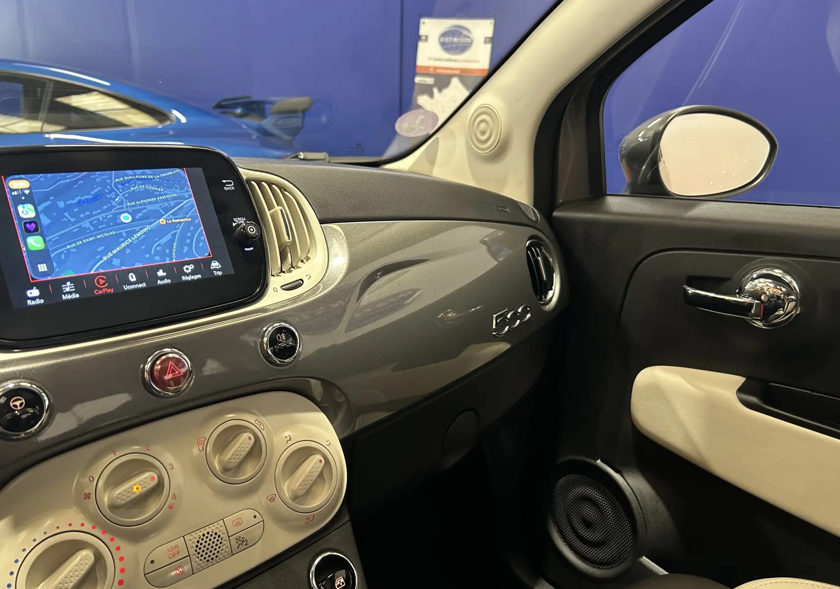 Vue intérieure côté passager de la Fiat 500 gris 2022 avec tableau de bord brillant et écran tactile affichant la navigation.