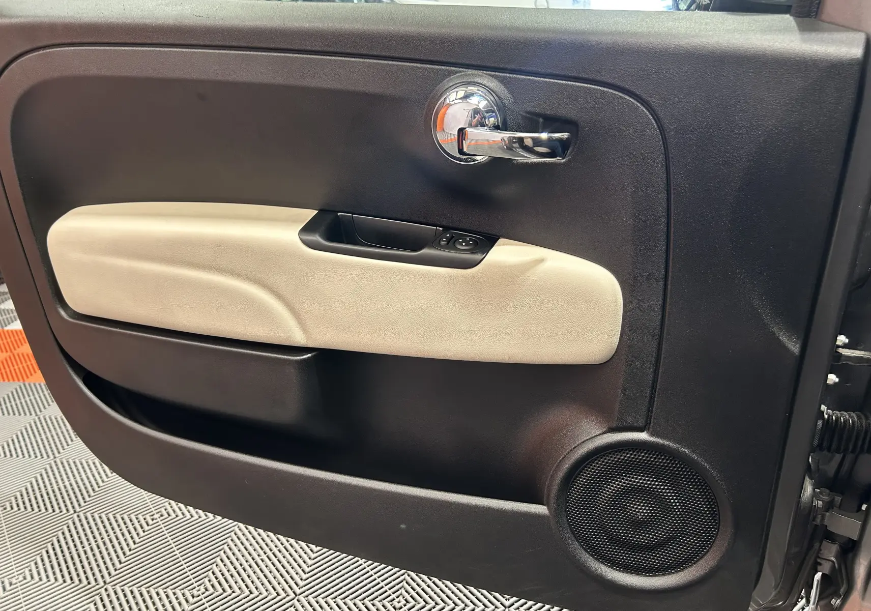 Intérieur de la porte côté gauche de la Fiat 500 gris, avec poignée chrome et habillage beige clair.
