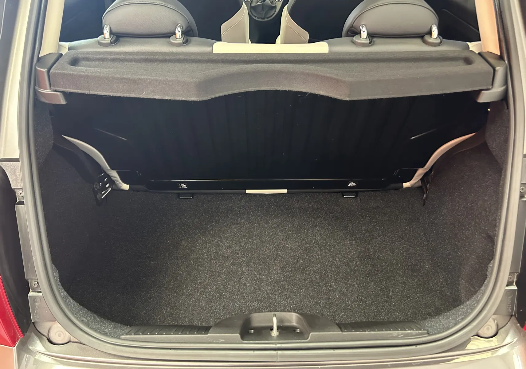 Vue arrière du coffre ouvert d'une FIAT 500 gris 70 Hybride BSG Dolcevita avec banquette arrière et habillage noir.