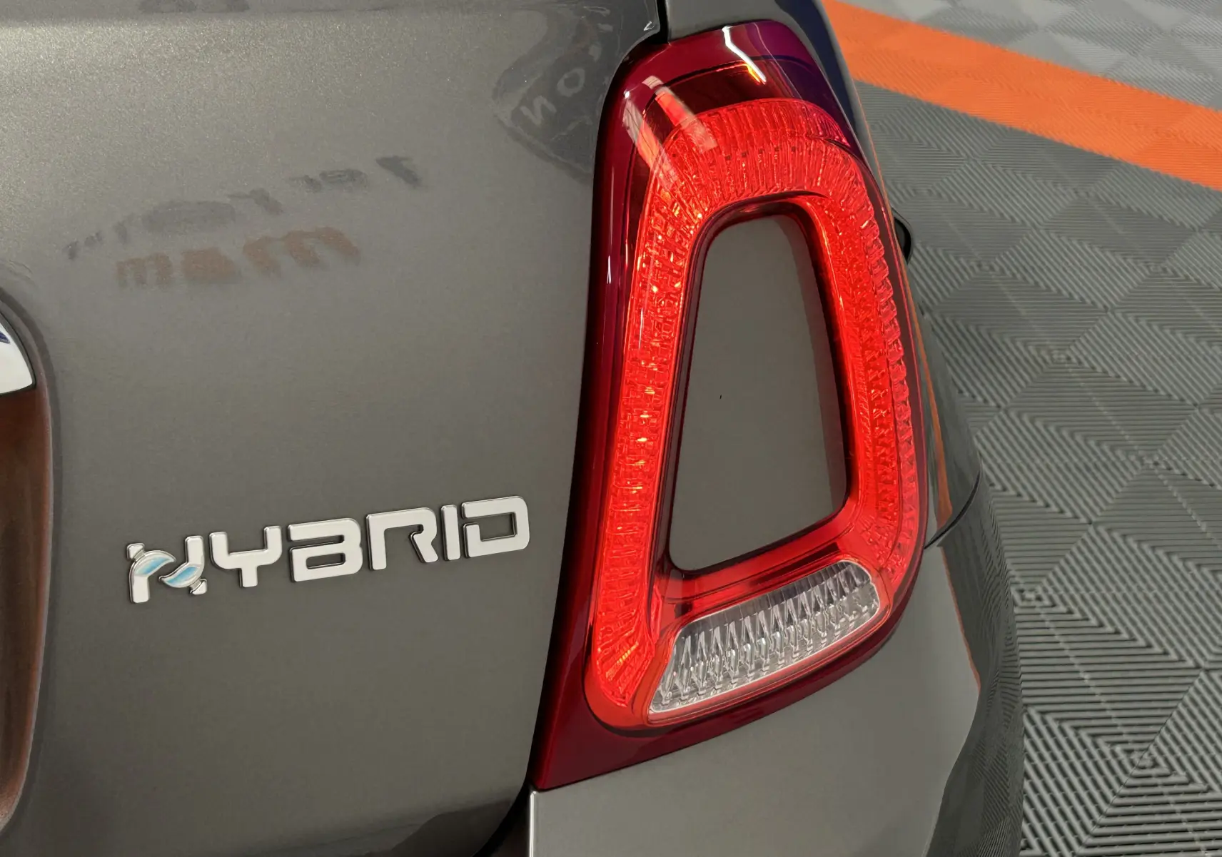 Gros plan sur le feu arrière droit et l’inscription "HYBRID" sur la partie arrière grise d’une Fiat 500 70 Hybride BSG DolceVita.