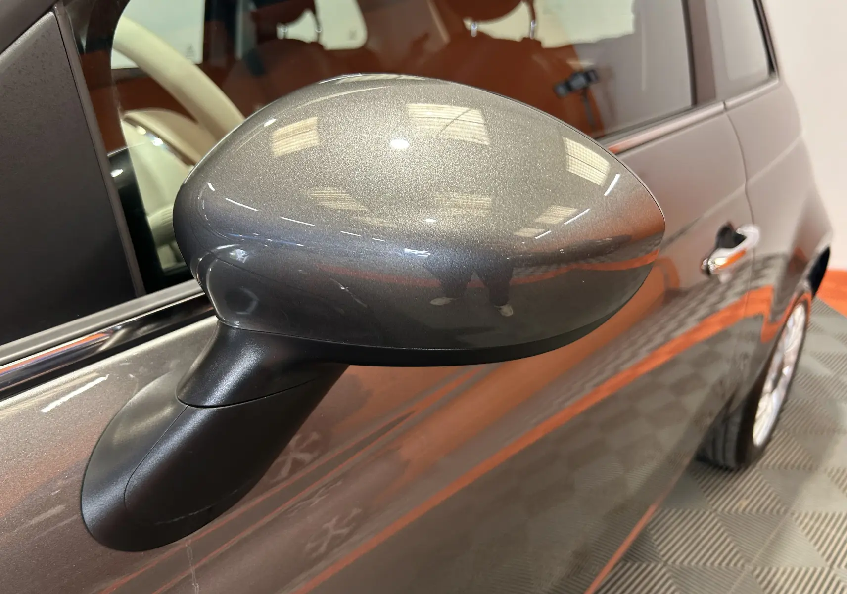 Rétroviseur côté gauche gris métallisé de la Fiat 500 hybride 2022, avec portière et partie avant visibles en léger flou.