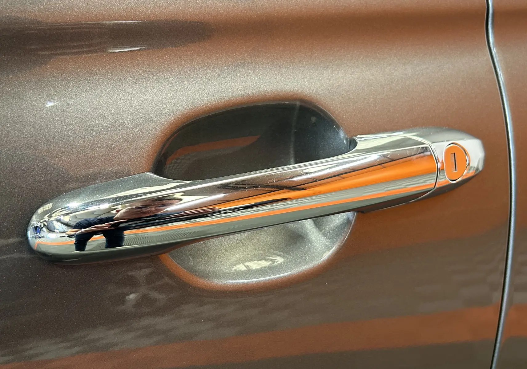 Poignée de porte chromée sur la portière gris métallisé d'une FIAT 500 70 Hybride BSG DolceVita, vue en gros plan.