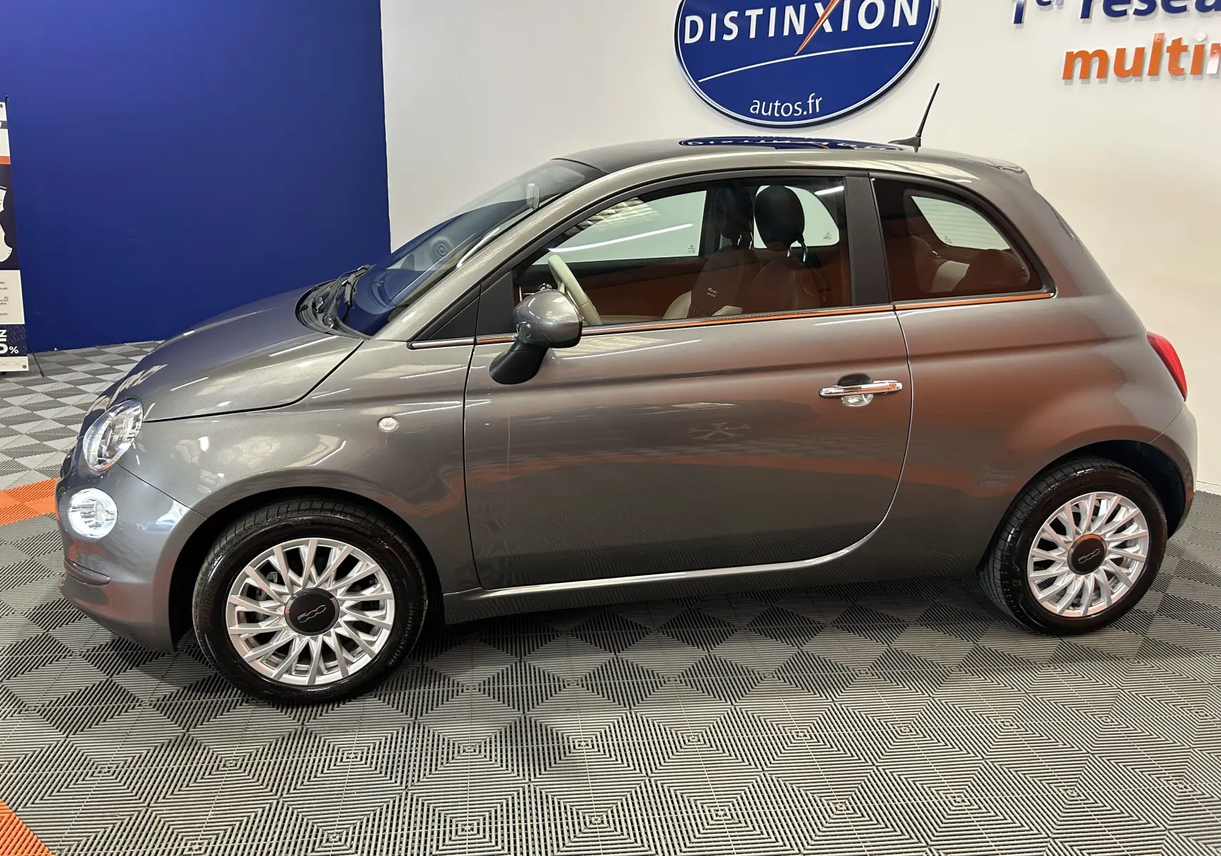 Profil droit d'une FIAT 500 gris métallisé 2022 avec toit panoramique, jantes alliage et intérieur clair visible.