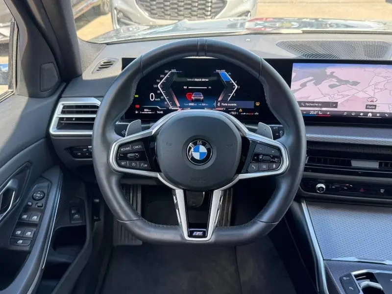 Vue intérieure centrée sur le volant M Sport et le tableau de bord numérique de la BMW Série 3 320dA xDrive 2025.