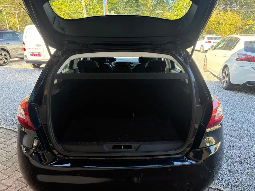 Vue arrière d'une Peugeot 308 Active noire de 2014 avec coffre ouvert, montrant l'espace de chargement vide.