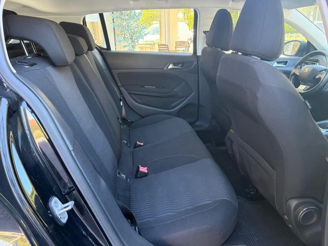 Intérieur arrière de la Peugeot 308 Active 2014 noir, vue côté gauche montrant les sièges en tissu et la portière ouverte.