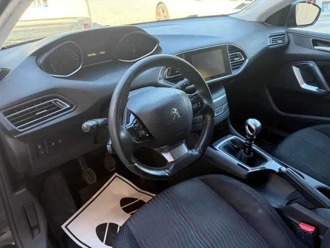 Vue intérieure de la Peugeot 308 Active 2014 noire, montrant le volant, tableau de bord et levier de vitesse manuel.