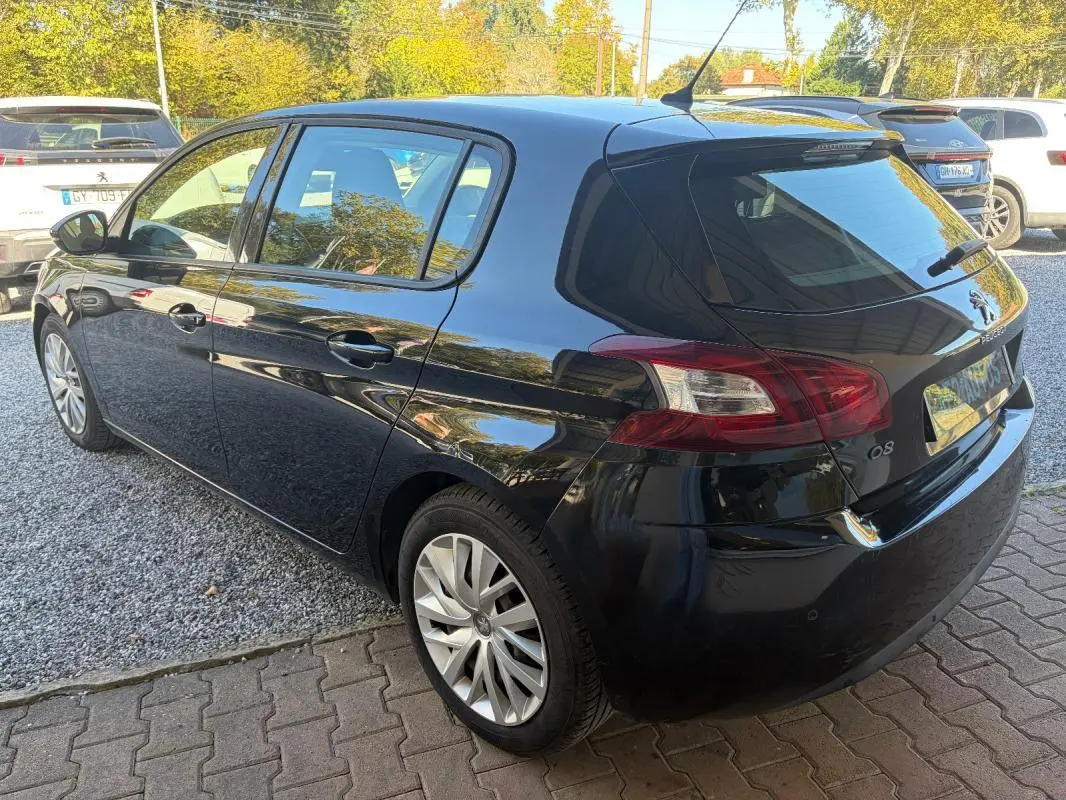 Peugeot 308 Active noire vue en 3/4 arrière droit, avec jantes alliage et feux arrière caractéristiques visibles.