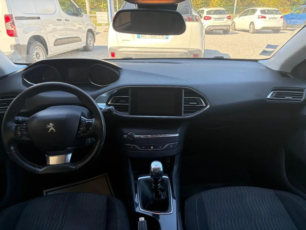 Intérieur noir de Peugeot 308 Active 2014, vue frontale du tableau de bord avec volant et levier de vitesses manuel.