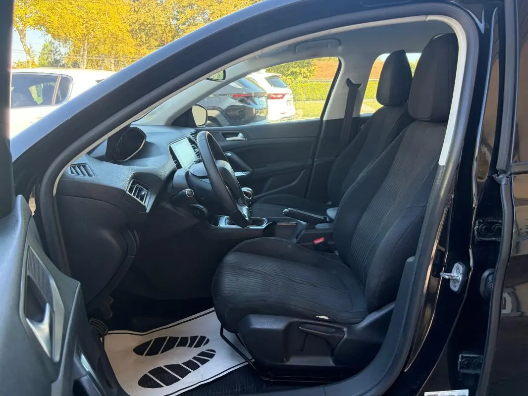 Intérieur côté conducteur d'une Peugeot 308 Active noire 2014, montrant sièges avant et tableau de bord.