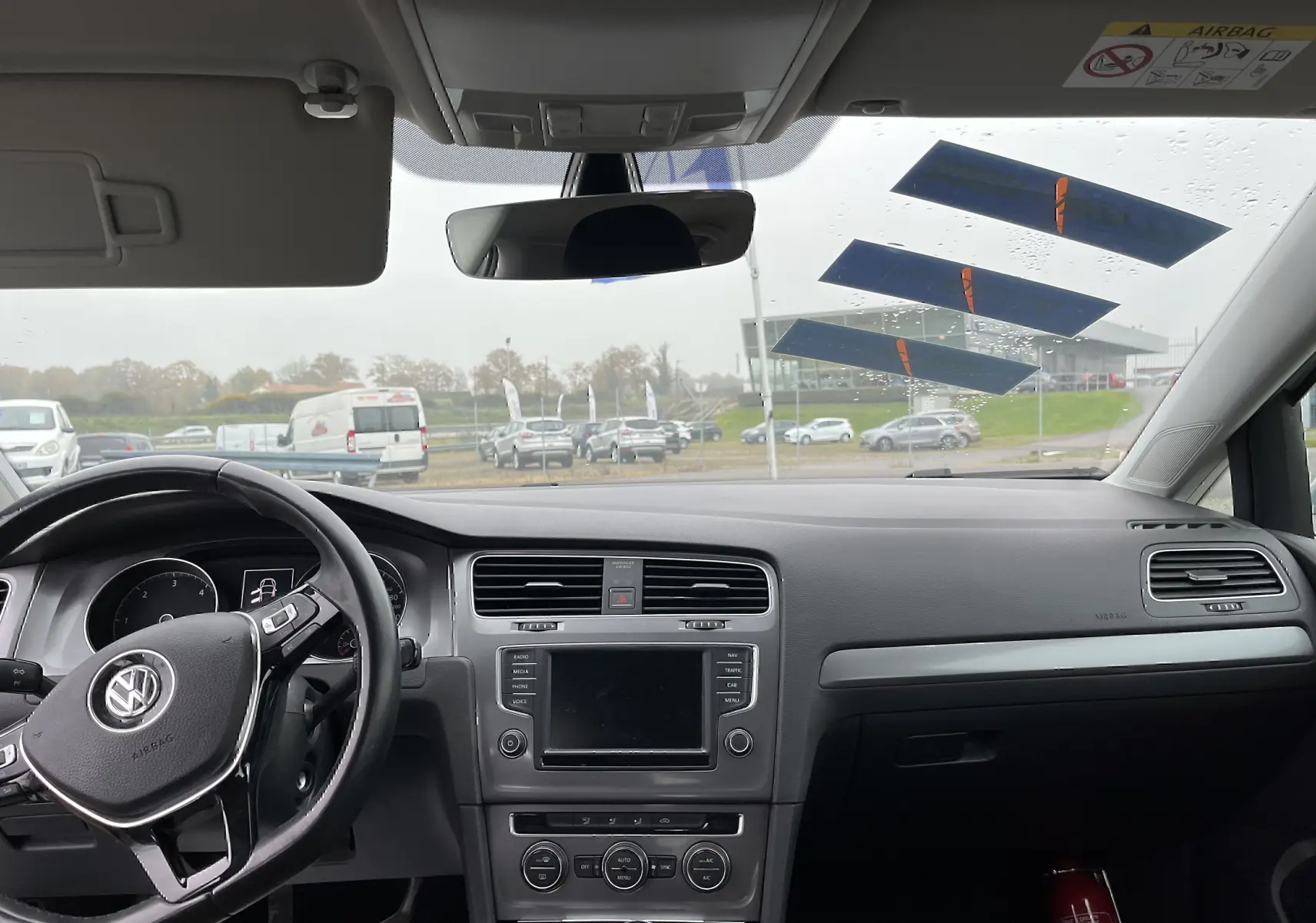 Vue intérieure avant de la Volkswagen Golf 7 argentée de 2017, montrant le tableau de bord et le volant multifonction noir.