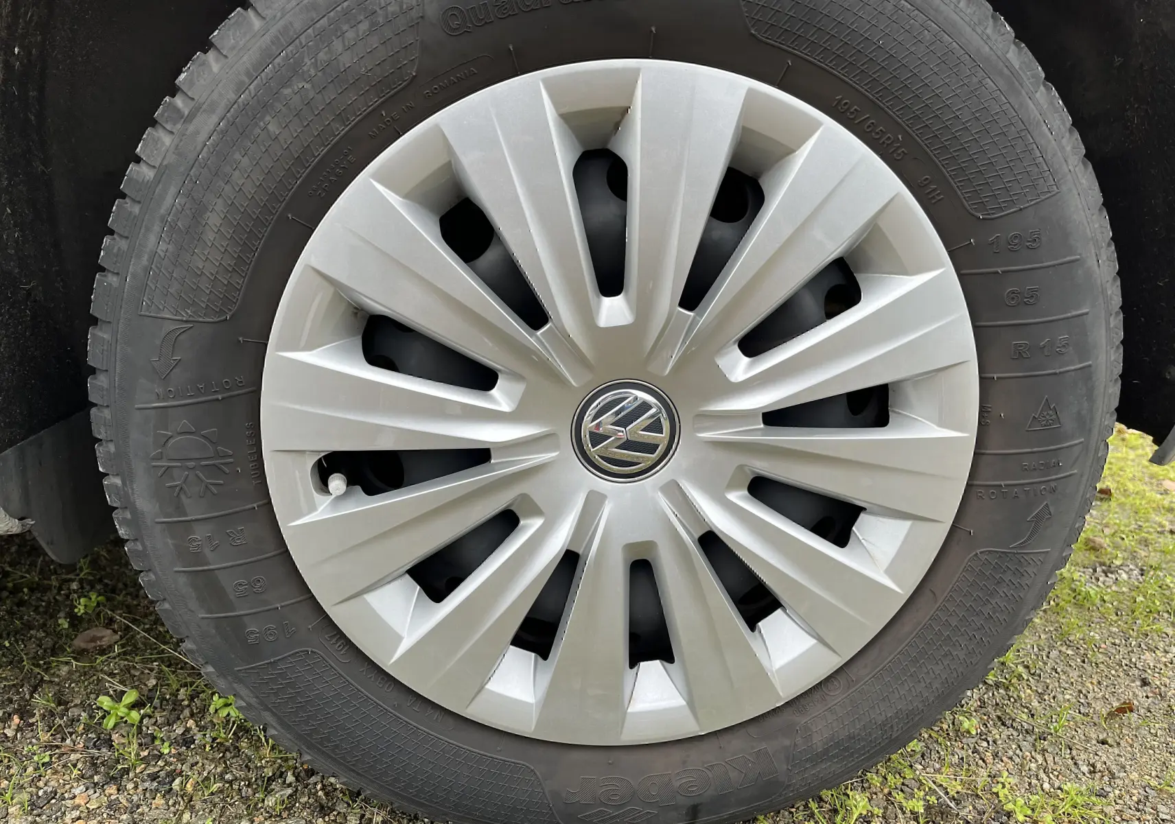 Gros plan sur la roue avant avec enjoliveur argenté et logo Volkswagen au centre, pneu marqué 195/65 R15.