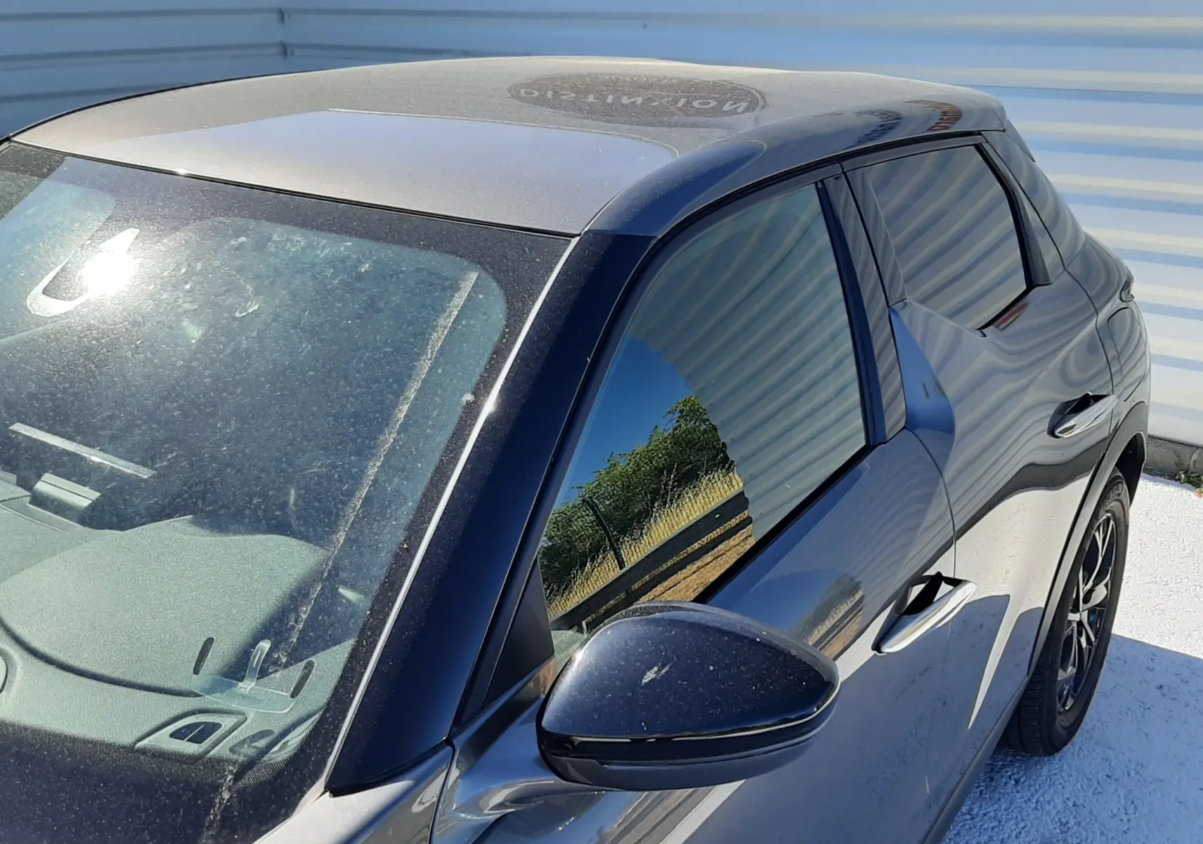 Vue 3/4 avant droit d'un DS3 Crossback gris foncé avec vitres teintées et rétroviseur noir brillant.