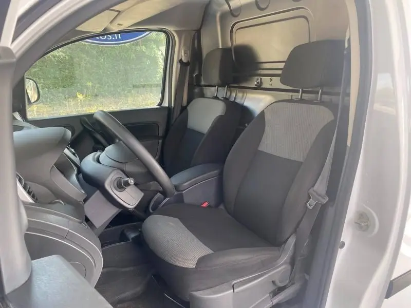 Vue intérieure côté conducteur du Renault Kangoo Express blanc 2022, sièges noirs avec tissu gris clair et cloison pleine arrière.
