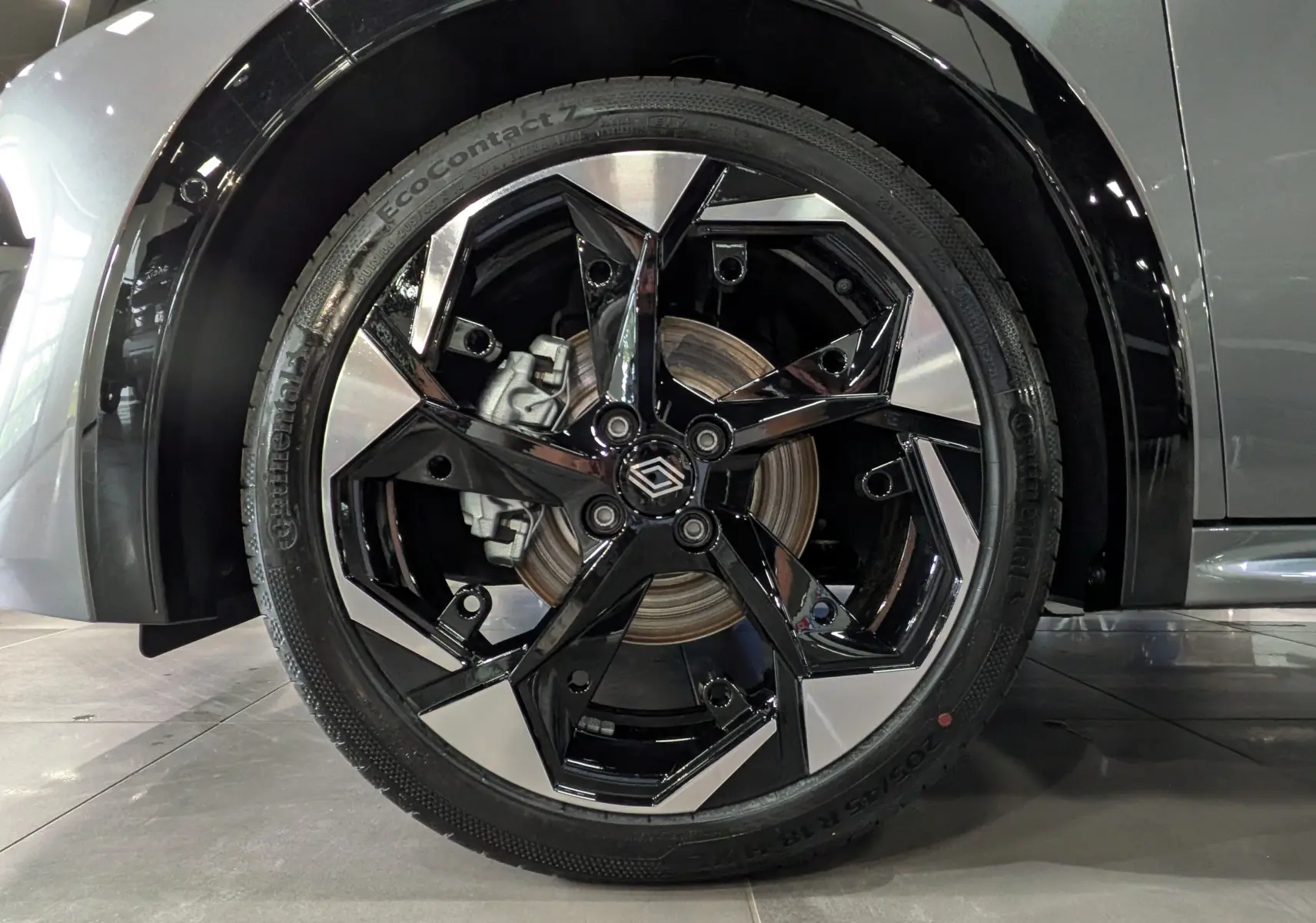 Gros plan sur la roue avant droite de la Renault Clio VI TCe 115 CH TECHNO gris schiste avec jante noire et argentée.