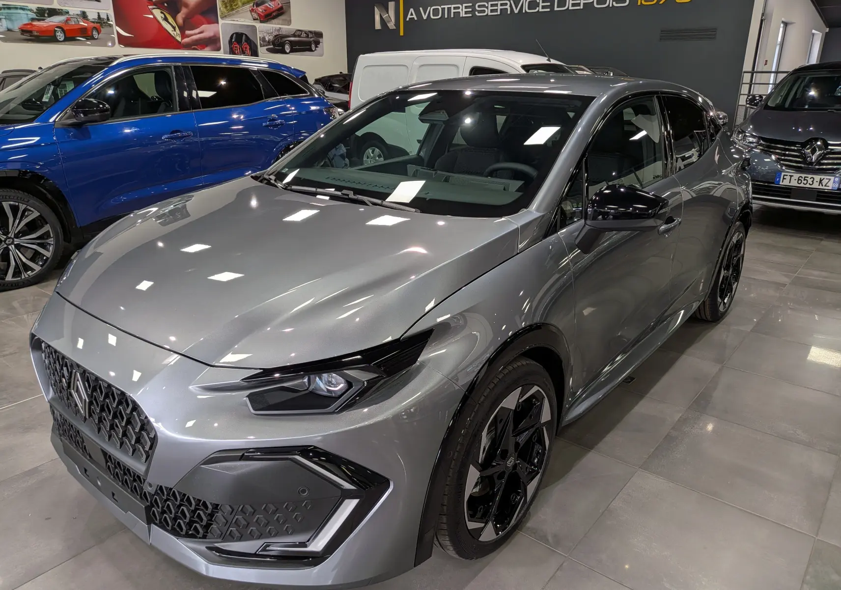 Vue 3/4 avant droite de la Renault Clio VI TCe 115 gris schiste avec jantes noires et calandre hexagonale en concession.