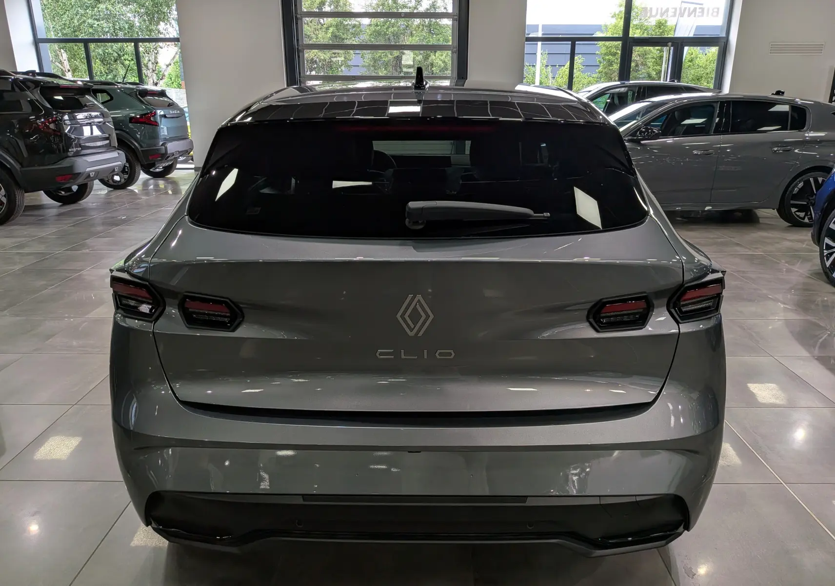 Vue arrière d'une Renault Clio VI TCe 115 CH TECHNO gris schiste, avec feux arrière LED et lunette arrière teintée.