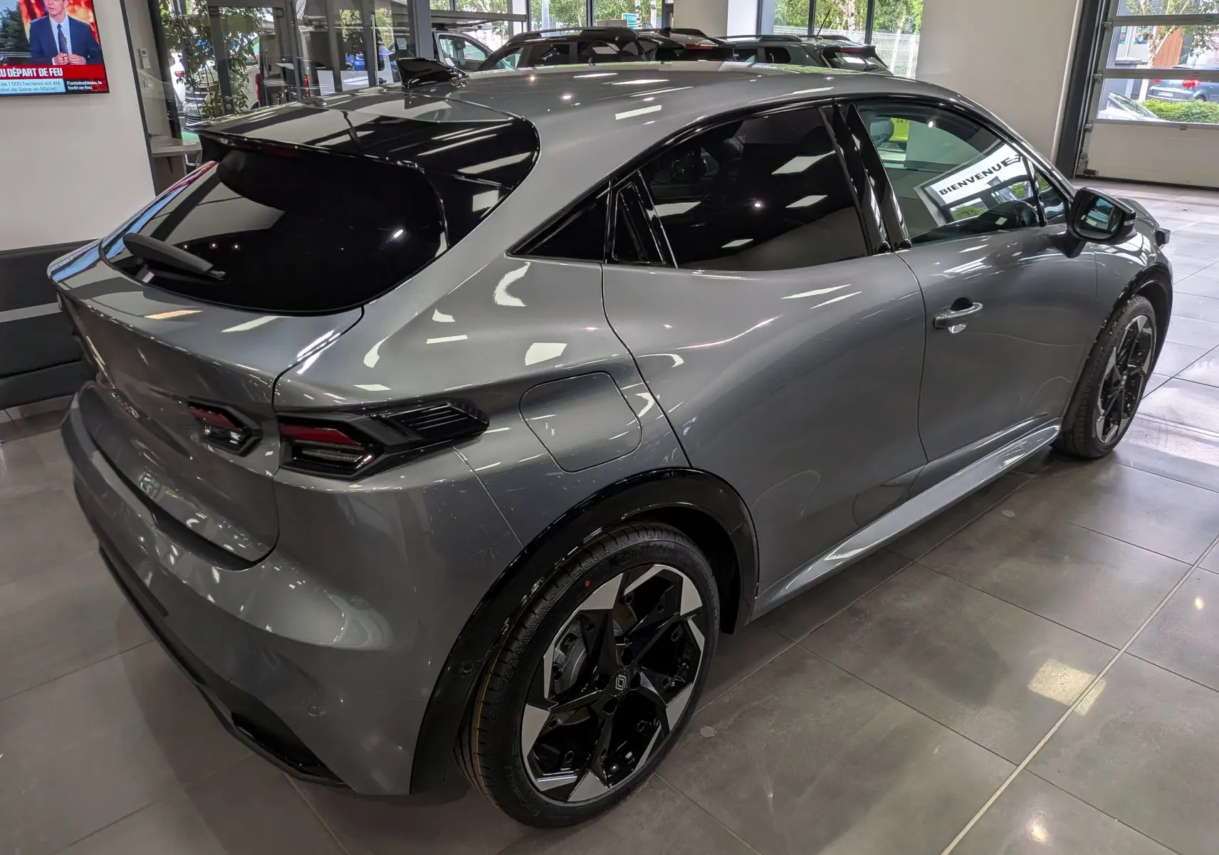 Vue 3/4 arrière droite d'une Renault Clio VI TCe 115 gris schiste avec toit noir et jantes bicolores en concession.