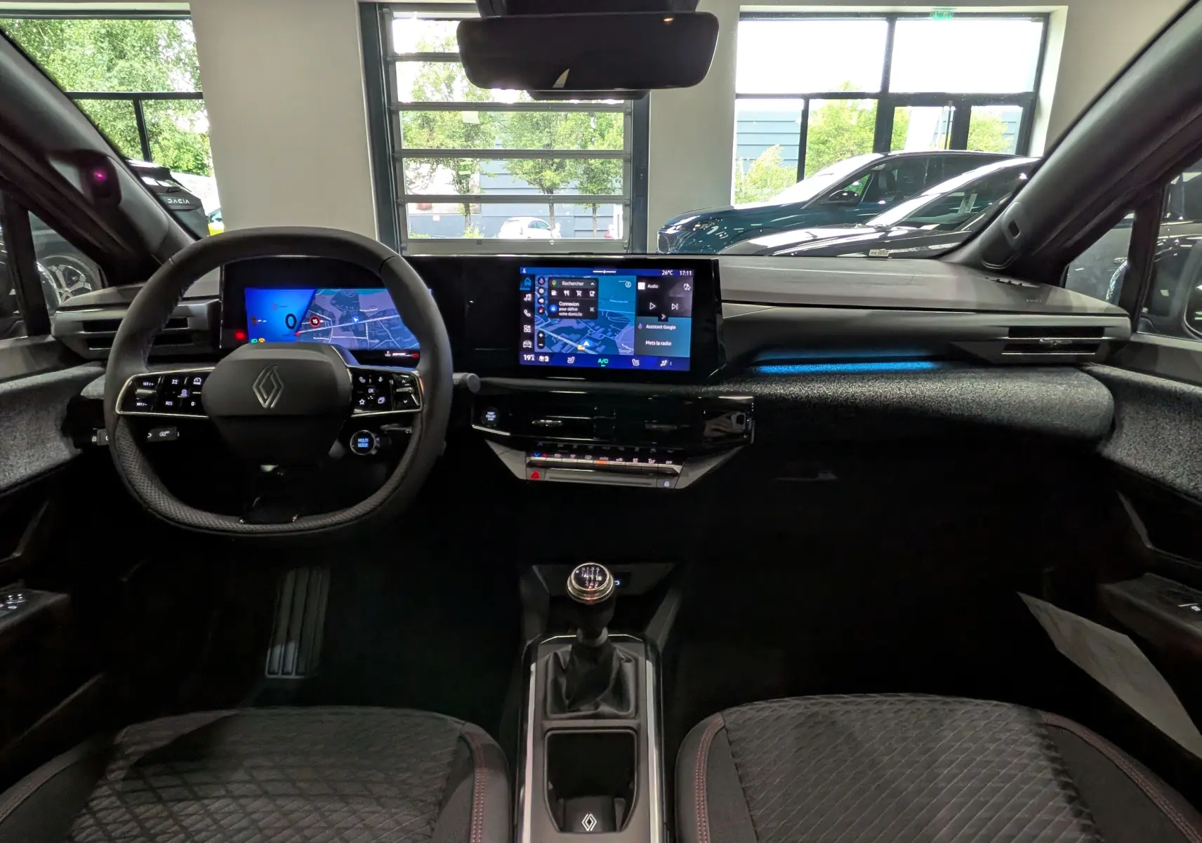 Vue intérieure avant de la Renault Clio VI TCe 115, tableau de bord moderne avec écran tactile et volant multifonction.